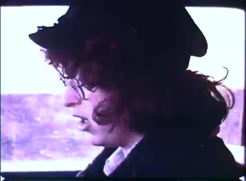 The still from the trailer of 'Harry and Tonto' features a character with curly hair, wearing glasses and a hat, inside a vehicle. The scene conveys a moment of contemplation or concern, possibly reflecting the film's themes of adventure and introspection. The 16mm print captures a nostalgic, vintage aesthetic typical of the era.
