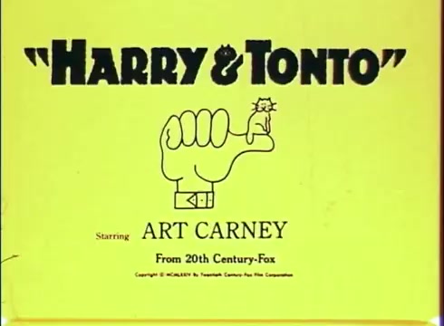 The still from the trailer of 'Harry and Tonto' features a bright yellow background with bold black text displaying the title 'HARRY & TONTO.' Below the title is a graphic of a hand forming a fist with a small cat perched on top. The name 'ART CARNEY' is prominently featured beneath, indicating the lead actor. The print is from 20th Century-Fox, suggesting a classic film aesthetic.