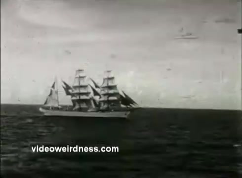 The still features a classic sailing ship with multiple masts navigating through the water. The image is in black and white, typical of the 1950s era, and captures the essence of maritime themes likely associated with the Coast Guard Academy. The background shows a cloudy sky, adding to the dramatic atmosphere of the sea scene.