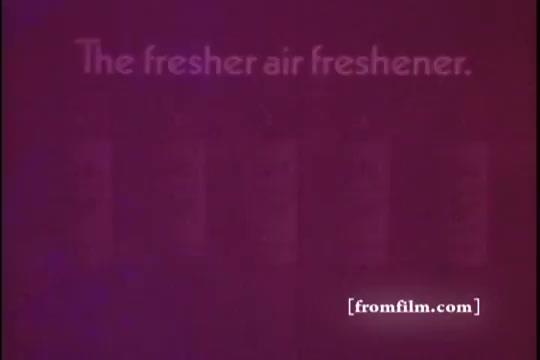 The still features a purple-tinted background with the text 'The fresher air freshener.' prominently displayed. In the lower portion, there are five indistinct bottles lined up, suggesting a product focus. The aesthetic is characteristic of 1970s advertising, with bold colors and simple messaging aimed at promoting a rug shampoo as an air freshener.