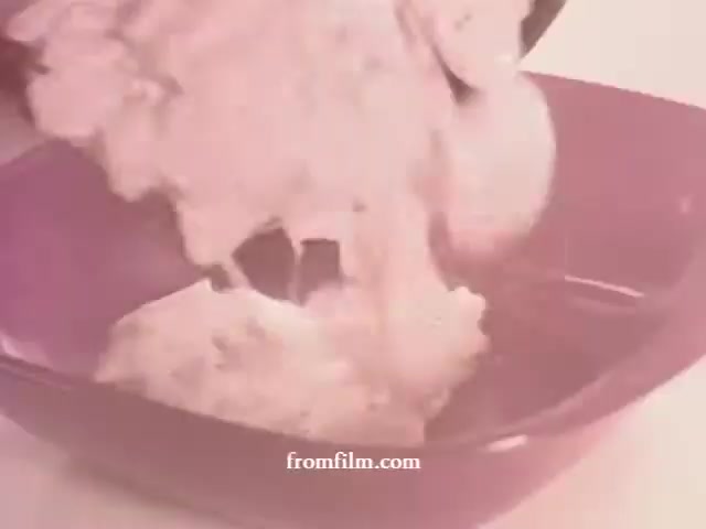 The still depicts a close-up of creamy mashed potatoes being poured into a purple bowl. The texture appears smooth and rich, highlighting the dish's appeal in the context of the 1970s Betty Crocker promotion. The overall visual has a slightly faded, nostalgic quality typical of 16mm film, enhancing the retro aesthetic.