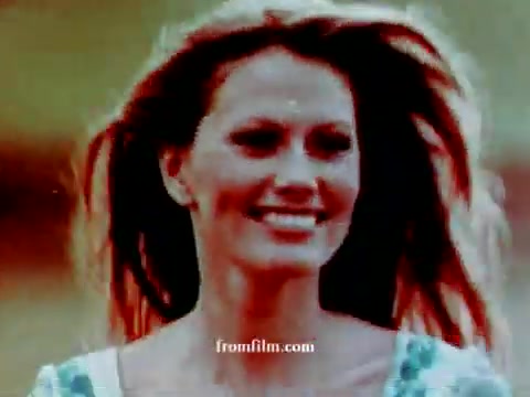 The still features a smiling woman with flowing hair, captured in a vibrant, nostalgic color palette typical of the early 1970s. The background is softly blurred, emphasizing her joyful expression. The overall tone conveys a sense of freedom and adventure, aligning with the spirit of the Volkswagen commercial.