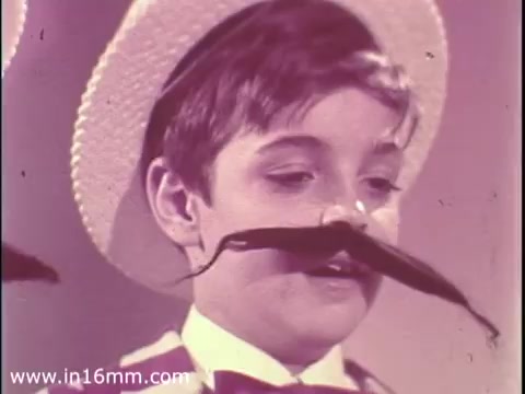 The still features a young boy wearing a straw hat and a formal outfit, complete with a bow tie. He has a playful expression, accentuated by a large, stylized fake mustache. The background has a soft focus, creating a whimsical atmosphere. This scene is likely intended to convey a lighthearted or humorous message, typical of a PSA aimed at encouraging participation in The Boys Club in 1968.