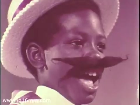 The still features a young boy wearing a straw hat and a playful, oversized mustache. He appears to be joyfully engaging, possibly performing or speaking, with a bright and lively expression. The visual style reflects the era of 1968, with a focus on whimsy and charm, characteristic of public service announcements aimed at promoting positive youth interactions and community involvement, particularly within The Boys Club.