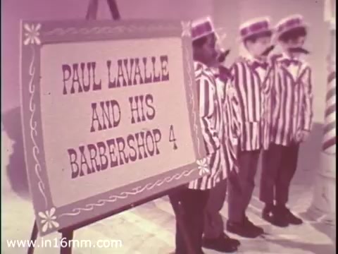 The still features a colorful sign reading 'PAUL LAVALLE AND HIS BARBERSHOP 4,' displayed prominently behind a group of boys dressed in striped outfits. The boys stand attentively, suggesting a performance or presentation. The image has a vintage aesthetic typical of 1968, likely from a public service announcement promoting The Boys Club.