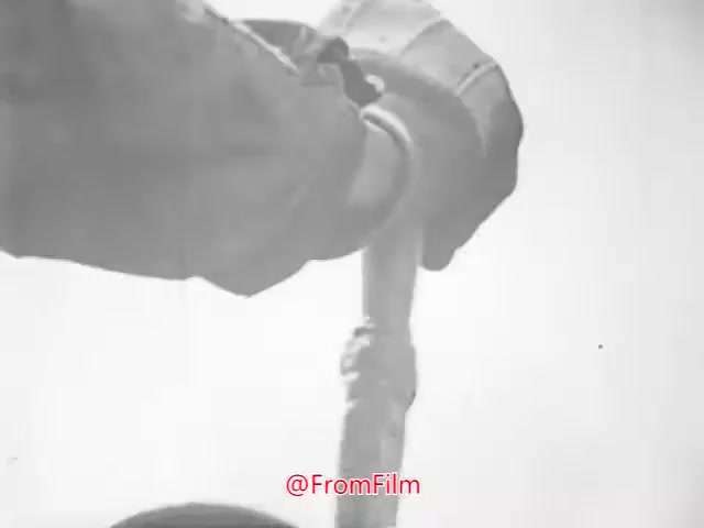The still from 'Project CARE PSA - 1960's' features a close-up shot of a hand gripping a device or tool, set against a light background. The hand is gloved, suggesting a focus on safety or preparedness. The context hints at a public service announcement, aimed at raising awareness or promoting care in some capacity. The monochrome quality reflects the era of the film.