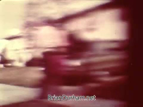 The still shows a blurred scene typical of a 16mm film capture, likely depicting outdoor activity or movement. The colors are soft, suggesting it may be an older film. The context implies a focus on safety, possibly illustrating a scenario promoting awareness or caution.