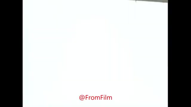The still features a bright, overexposed background with a faint outline of a film transfer setup. The focus is on the process of converting 16mm film to video, emphasizing the technical aspects. The @FromFilm logo is prominently displayed at the bottom, indicating the source of the production. The overall composition reflects an informal behind-the-scenes glimpse into the film transfer process.