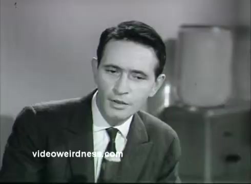 The still features a man in a suit, seated and looking seriously into the camera. He has a contemplative expression, suggesting he is delivering an important message. In the background, there is a vintage setting, likely indicative of the time period, with simple furnishings. The overall tone suggests a focus on education or awareness about kidney disease, typical of a public service announcement.