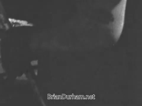 In this still from the 'Jerry Lewis Muscular Dystrophy PSA,' Arnold Hughes is depicted working diligently under the sun, showcasing his strong muscles as he performs manual labor. His focus and strength represent his commitment to providing for his family, particularly his son, Spunky, who struggles with muscular dystrophy and cannot engage in physical activities independently. The image conveys a poignant contrast between Arnold's physical abilities and his son's limitations.