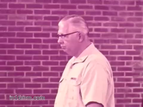 The still from the 16mm print of the 'West Virginia Safety Council PSA' features a middle-aged man with glasses, walking against a brick background. His expression is serious, reflecting the importance of vehicle safety. The color tone is slightly faded, typical of older film formats, and the overall scene emphasizes a focus on safety inspections from the 1960s.