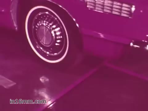 The still from the 16mm print of the 'West Virginia Safety Council PSA' features a close-up of a vehicle's wheel. The image is dominated by a purple hue, giving it a distinct retro aesthetic typical of films from the 1960s. The focus on the wheel emphasizes vehicle safety, likely highlighting the importance of proper maintenance and inspections, which aligns with the PSA's intended message about automotive safety practices.
