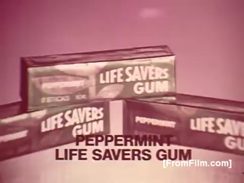 The still features several boxes of Life Savers Gum arranged in a triangular formation against a soft pink background. The prominent text at the bottom reads 'PEPPERMINT LIFE SAVERS GUM,' emphasizing the flavor. The vintage aesthetic reflects the 1970s style, with a focus on bold colors and clear branding. The gum is packaged in a sleek box, indicating its appeal as a unique product from the time.