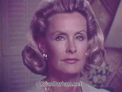 The still features a woman with classic 1970s hairstyle and makeup, looking directly at the camera with a serious expression. The background appears to be softly blurred, suggesting a domestic setting. The tone conveys a sense of urgency and importance, characteristic of public service announcements from that era focused on health awareness, specifically juvenile diabetes.