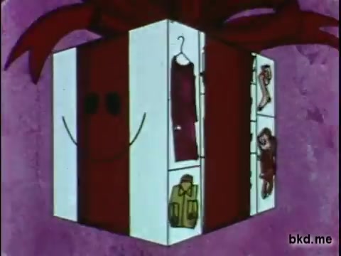 The still depicts a cheerful, animated gift box adorned with a large red bow, featuring a smiling face. The box is designed with sections showing various clothing items, indicating a focus on fashion and presents. The background is a soft purple, enhancing the festive theme, typical of holiday commercials or promotions.