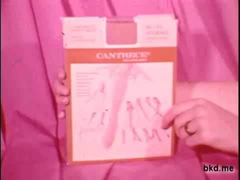 The still features a pink backdrop, where a person's hand is holding a product box labeled 'CANTRECE.' The box appears to showcase illustrations or instructions related to the product, which seems to be associated with women's fashion or clothing items. The vintage aesthetic suggests a mid-20th century context, typical of television or movie theatre commercials from that era.