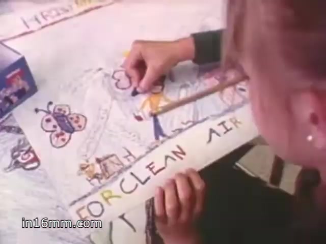 The still from the 'Christmas Seals 1981 PSA' features a child actively drawing on a large piece of paper, which displays colorful illustrations including butterflies and figures. The text 'FOR CLEAN AIR' is prominently written, emphasizing a message related to environmental awareness or health. The setting appears casual and creative, suggesting a focus on children's involvement in important social causes.