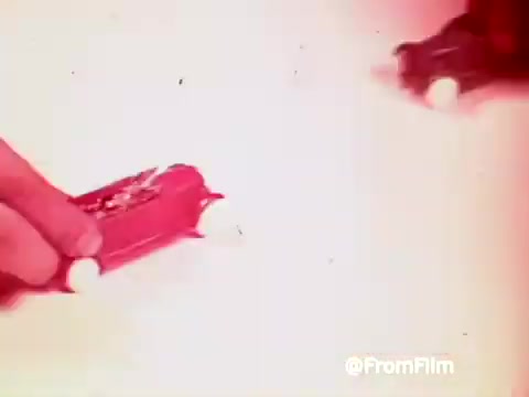 The still from the 1960s 'Archies Alpha Bits' commercial features colorful toy cars being manipulated by a hand. The scene emphasizes the fun and playful nature of the promotional content, likely aimed at capturing the attention of children in relation to Post Alpha Bits cereal. The vibrant colors and dynamic presentation suggest a lively and engaging advertisement.