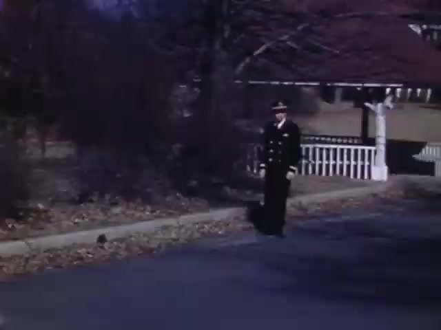 The still from 'Jack #2' features a man in a military uniform standing on a suburban street. The scene, captured on Kodachrome film likely between 1941 and 1943, showcases muted autumn colors with bare trees and a white picket fence in the background. The atmosphere suggests a reflective or nostalgic moment, typical of home movies from that era.