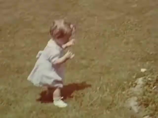 The still from 'Connie & Patty #2' features a small child in a light-colored dress, playing in a grassy area. The vibrant colors and the child's playful stance suggest a joyful, carefree moment. Given the Ansco film stock, it likely dates to the 1940s, potentially around the World War II era, when such home movie styles were popular. The simplicity of the scene captures a nostalgic innocence typical of that time.