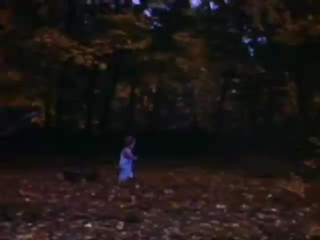 The still from 'Connie & Patty #2' features a child running through a wooded area covered in autumn leaves. The vibrant colors suggest a warm tone, typical of Ansco film. Given the context and the child's attire, it likely dates around the World War II timeframe, possibly the 1940s. The natural setting and playful theme reflect a nostalgic, simpler era.