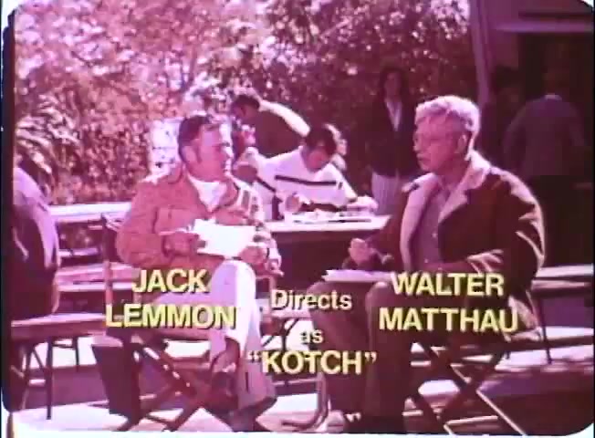 The still features a scene from the film 'Kotch,' directed by Jack Lemmon and starring Walter Matthau. Two men are seated at an outdoor table, engaged in conversation. The background shows people casually interacting in a sunny, relaxed setting. The color is vibrant, typical of a 16mm print, with the titles prominently displayed in yellow text.