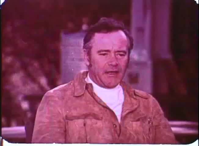 The still features Walter Matthau in a casual outfit, consisting of a light brown jacket and a white shirt. He appears to be in a relaxed setting, possibly speaking or reflecting. The background is slightly blurred, suggesting a focus on Matthau's expression. The colors have a faded quality typical of a 16mm print, enhancing the nostalgic feel of the promotional material for 'Kotch.'