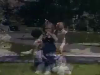 The still from 'Connie and Shirley reel #1 - 1941' features a group of children playing outdoors. They are engaged in a fun, lively moment, possibly posing for the camera. The scene has a nostalgic quality, typical of Kodachrome film from the early 1940s, showcasing vibrant colors and a cheerful atmosphere. The background includes greenery, suggesting a park or backyard setting.