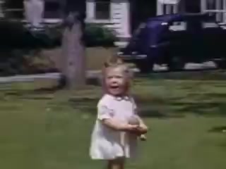 The still features a young girl in a white dress playing in a grassy area, presumably a yard. She holds a doll and appears joyful, laughing or calling out. In the background, a vintage car and a house are visible, indicative of suburban life in 1941. The vibrant colors capture the nostalgic essence of childhood and the era.