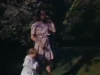 The still captures a moment from the 1941 film 'Connie and Shirley.' It features a woman in a light-colored dress alongside a young child, dressed in a white outfit. They appear to be outdoors, surrounded by greenery that suggests a sunny, pleasant day typical of that era. The Kodachrome film quality adds a vibrant and nostalgic color tone, highlighting the innocence and warmth of the scene.