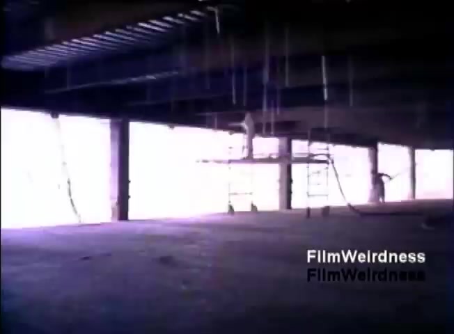 The still depicts a dimly lit, partially constructed interior space, likely a commercial building. Exposed beams and wiring are visible, with a significant amount of natural light streaming in from large, unfinished windows. The atmosphere suggests ongoing construction or renovation, providing a backdrop for the IBM System 36 sales narrative.