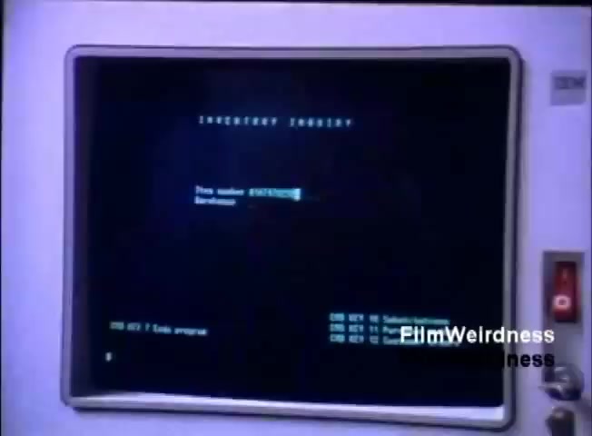 The still features a vintage IBM computer screen displaying an 'Inventory Inquiry' prompt. The screen shows a black background with white text indicating the action of entering a specific item number for inquiry. The interface appears basic and functional, characteristic of early computer systems, with a simple layout and command lines visible at the bottom. The IBM logo is visible on the monitor frame, emphasizing the brand.
