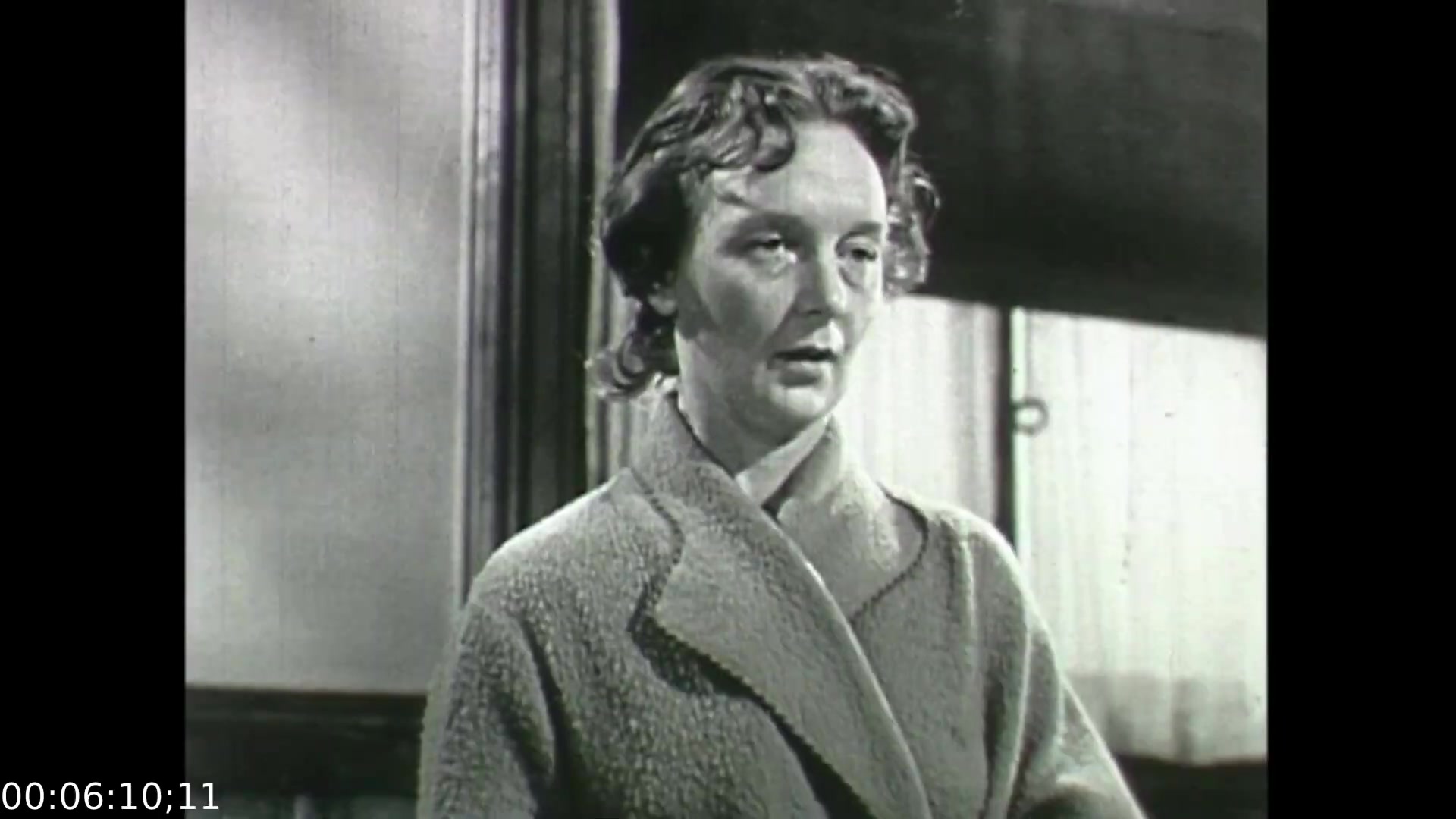In this still from 'Feelings of Depression' (1950), a woman appears to be in a state of emotional distress. Her facial expression suggests vulnerability and introspection, reflecting the film's exploration of mental health issues. The setting likely indicates a clinical or therapeutic environment, aligning with the film's objective to educate viewers about depression through the narrative of John Murray, a businessman dealing with despondency. The overall mood conveys the seriousness of the subject matter, emphasizing the challenges faced by individuals grappling with mental health.