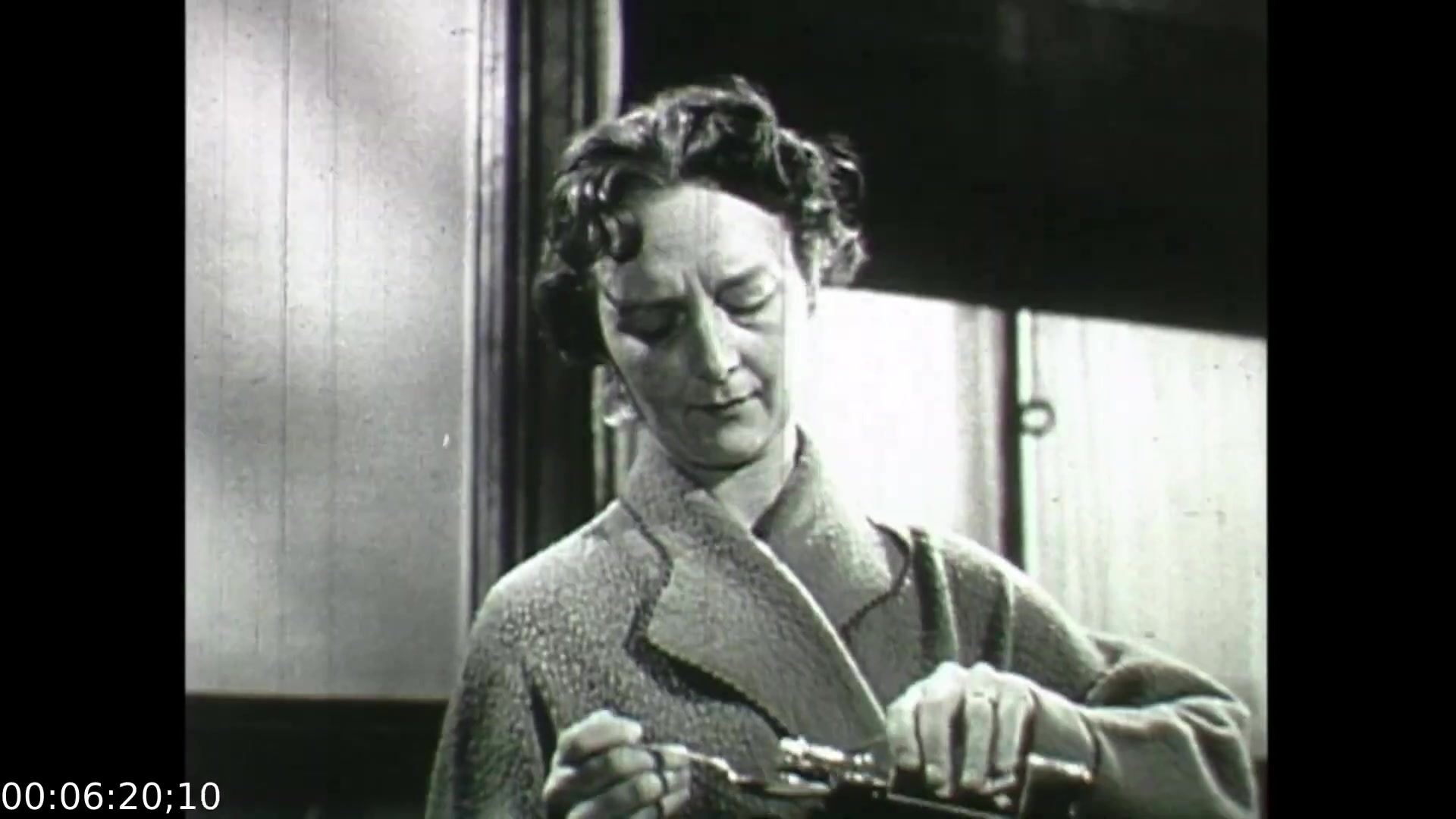 In this still from 'Feelings of Depression' (1950), a woman is depicted focused on a task, likely related to home or caregiving. Her expression suggests introspection or concern, reflecting the emotional undertones of the film, which explores the effects of depression on individuals and their families. The film serves as an educational piece, portraying the societal challenges around mental health in the 1950s.