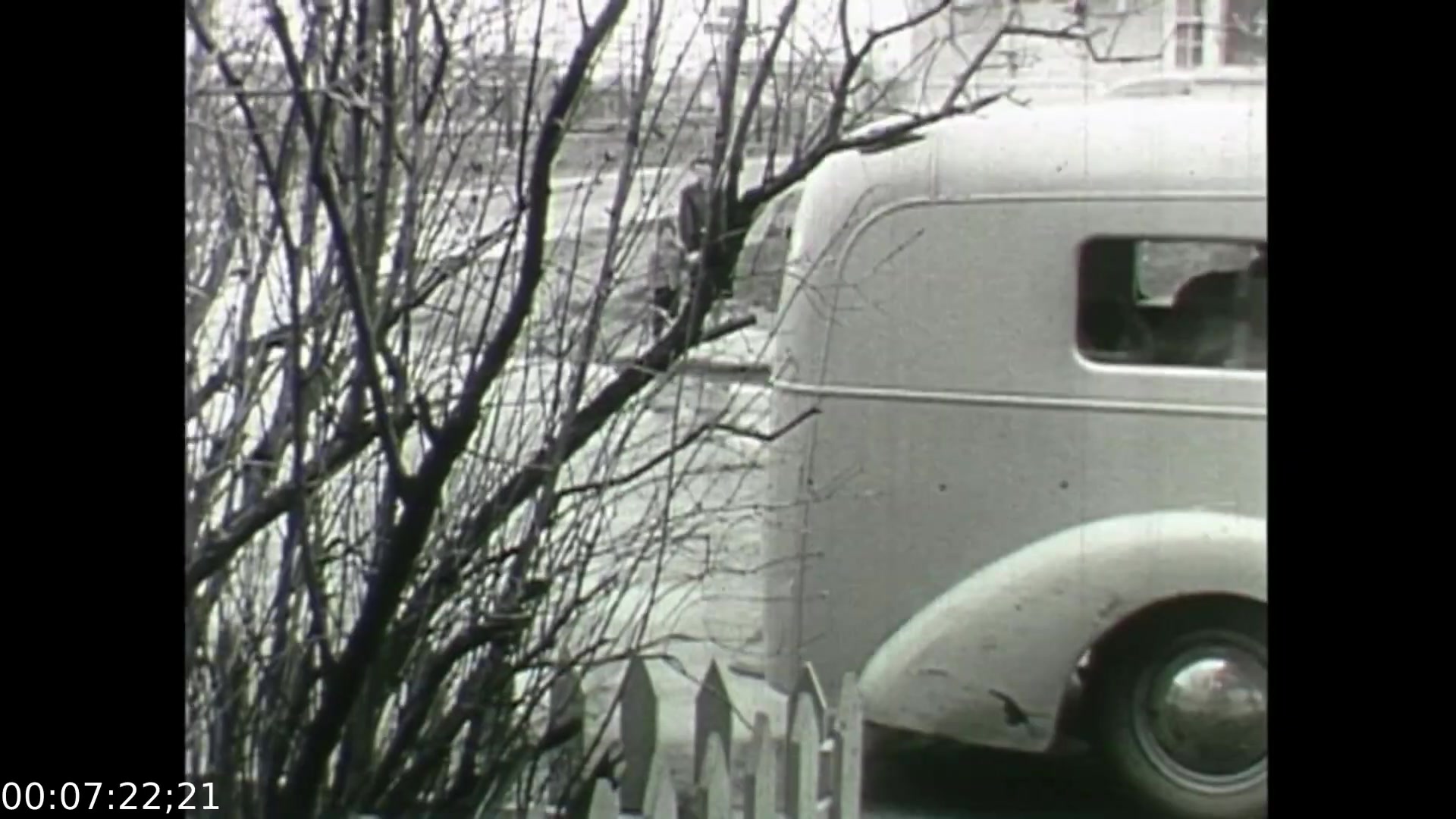 The still from 'Feelings of Depression' (1950) depicts a bleak, wintery scene with bare trees and a vintage automobile. The image is shot in black and white, characteristic of the era, conveying a somber mood. This visual ambiance complements the film's exploration of John Murray's struggles with depression, emphasizing themes of isolation and emotional hardship. The presence of the car and the surrounding environment suggests the context of 1950s suburban life, while the starkness of the trees mirrors Murray's internal despondency.