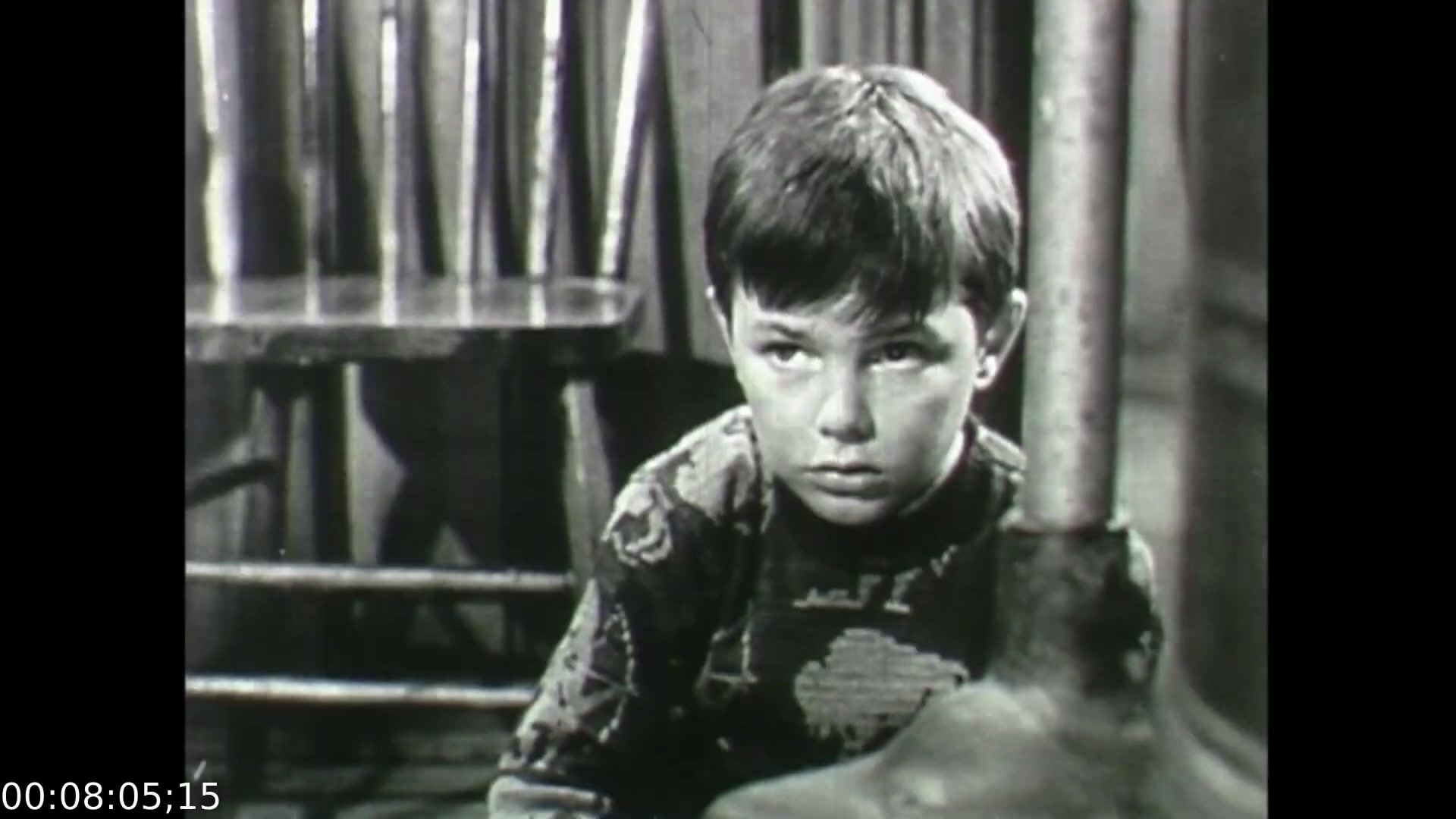 The still from 'Feelings of Depression' (1950) depicts a young boy with a concerned expression, conveying a sense of distress or introspection. The muted tones and simplicity of the setting emphasize the theme of emotional struggle, likely reflecting the impact of familial or societal pressures. This visual element supports the film's narrative about mental health, illustrating how early emotional challenges can manifest in youth. The overall atmosphere is somber, aligning with the film's focus on the complexities of depression.
