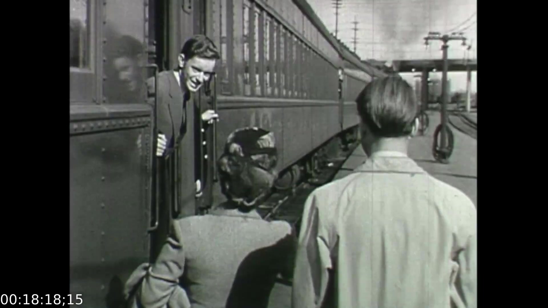The still from *Feelings of Depression* (1950) shows a train station scene, with a young man leaning out of a train door, smiling as he interacts with a woman in a hat and gloves. Two other figures, one facing away, seem to be engaged with her. The composition captures a moment of human connection and potential departure, subtly reflecting the emotional complexities explored in the film regarding mental health and depression. The black-and-white aesthetic emphasizes the historical context of the era.