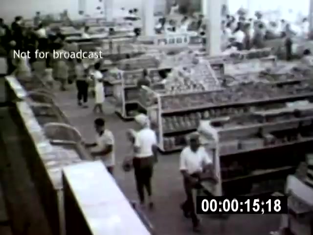 The still from 'Brazilia' depicts a bustling supermarket filled with shoppers navigating through aisles brimming with goods. Shot from a high angle, the scene conveys a sense of organized chaos, showcasing the modern consumer culture in Brazil during that era.