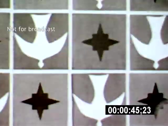 The film still from 'Brasilía' features a close-up, abstract pattern of shapes resembling stylized birds and stars, arranged in a grid. The setting suggests a focus on design elements characteristic of Brazilian modernism, emphasizing geometric forms and bold contrasts.