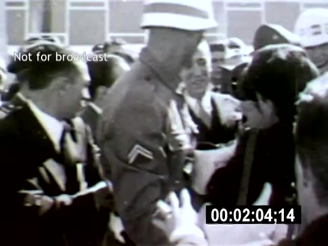 The film still from 'Brazilia' captures a tense interaction between a military figure in uniform and a civilian, amidst a crowd of onlookers in a city setting. The camera angle suggests an intimate yet chaotic scene, emphasizing the confrontation and the surrounding authorities' attention.