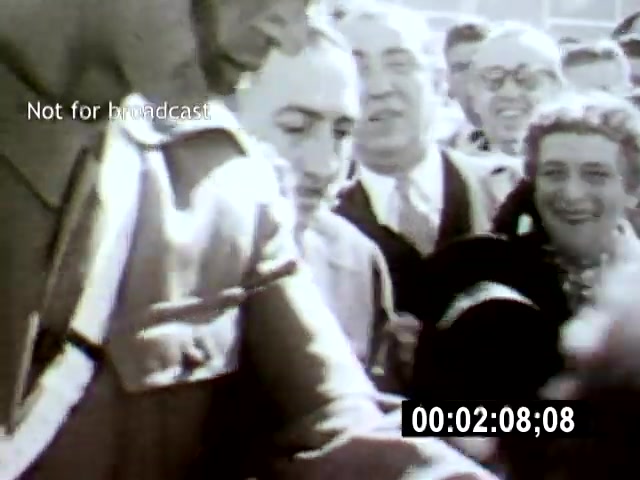 The still captures a crowd gathered around a central figure, showcasing a mix of emotions and expressions, likely during a significant public event in Brasília. The camera angle is close, emphasizing the intimate interactions and reactions of the people, evoking a sense of connection to the moment.