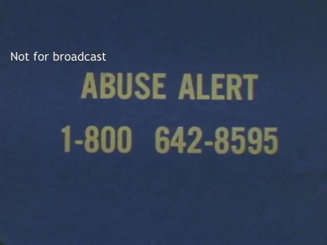 The film still features a blue background with bold yellow text reading 'ABUSE ALERT' followed by a contact number, emphasizing the urgency of the message. The straightforward camera angle focuses directly on the text, aiming to convey important information clearly and effectively.
