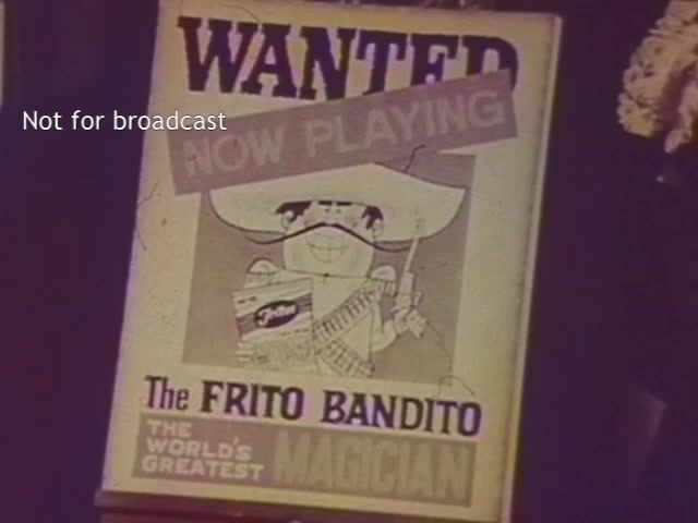 The still features a vintage poster displaying a character called 'The Frito Bandito,' depicted as a humorous cartoon figure wearing a sombrero and holding a bag of Fritos. The poster includes the words 'WANTED' and 'NOW PLAYING,' suggesting a playful promotional theme. It labels him as 'THE WORLD'S GREATEST MAGICIAN.' The image is colorized and marked 'Not for broadcast,' indicating it's for specific purposes and not intended for public airing.