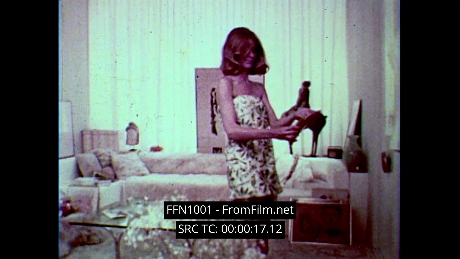 The still from the archival 16mm advertisement for Chanel No. 5 showcases a woman in a floral-patterned dress, engaging with the iconic perfume bottle. The scene is set in a softly lit, elegant living room, reflecting the dreamy and ethereal aesthetic typical of 1970s cinematography. Close-ups emphasize the allure of the product, creating a luxurious and enchanting atmosphere. Overall, the advertisement captures the essence of timeless elegance associated with Chanel.